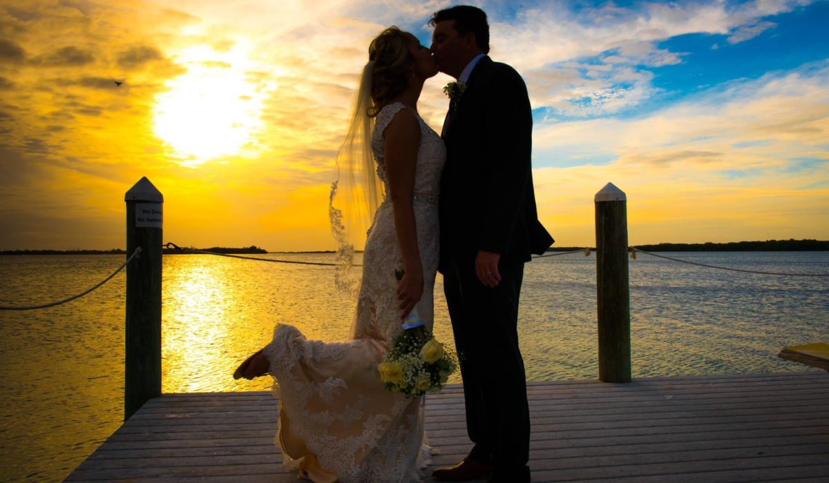 Bride and Groom Kissing on a Dock at Sunset