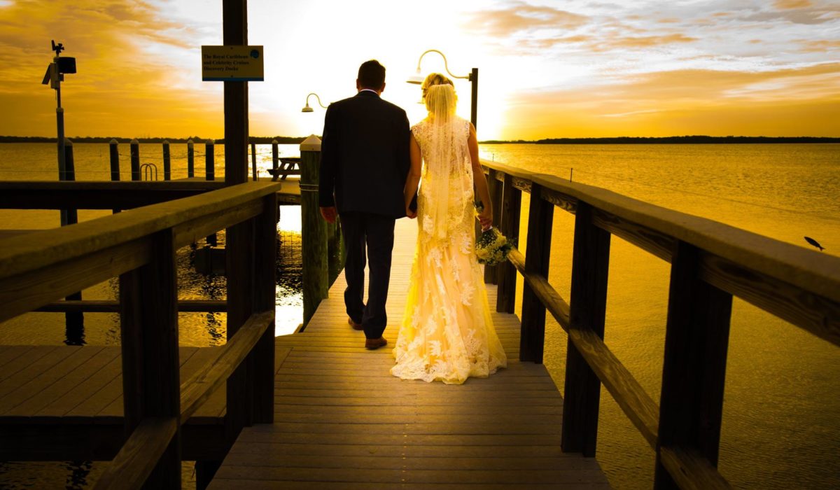 Bride and Groom Walking on a Dock at Sunset